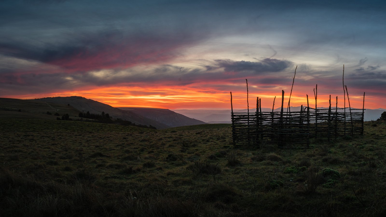 An orange sunset over the mountains and fields around Hogsback.